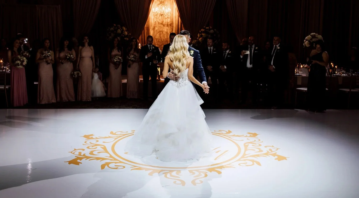 Newlyweds sharing their first dance on a custom gold-crest vinyl dance floor